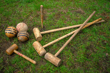 Vintage wooden croquet set with clubs and wooden balls on the green grass. Summer retro games.