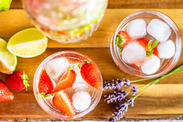 Fresh fruit summer drink with strawberry, lime and ice placed on wooden desk