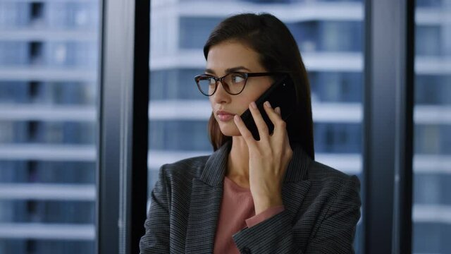 Displeased businesswoman talking on mobile phone with business partner in office