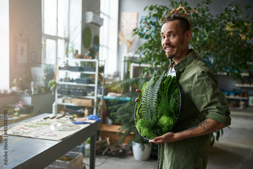 Wall mural joyful young man holding round tray with plants