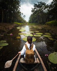 Woman explorer travels an Amazon river in a canoe - obrazy, fototapety, plakaty
