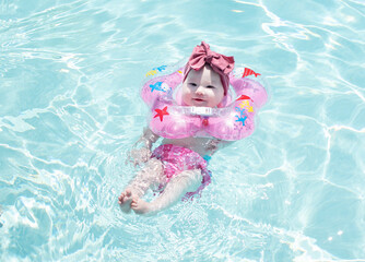 Baby swimming with neck swim ring in pool
