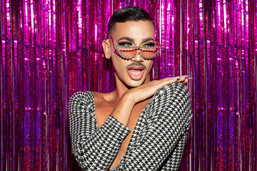 Closeup portrait of drag queen diva with fuchsia glitter background