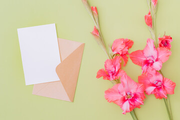 Mockup white wedding invitation and envelope with pink flowers on a green background