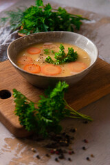Still life with homemade made split pea soup on grey background with fresh parsley leaves