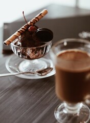 Chocolate ice cream with cherries, waffle tube and cookies in a glass plate in a cafe
