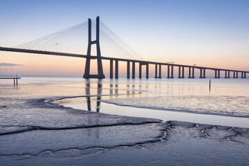 Architectural landmark Vasco da Gama Bridge over the Tagus River at dusk in Lisbon, Portugal. The...