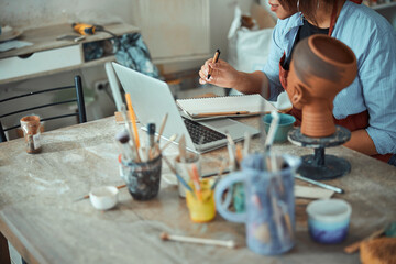 Female potter using notebook and taking notes in pottery workshop