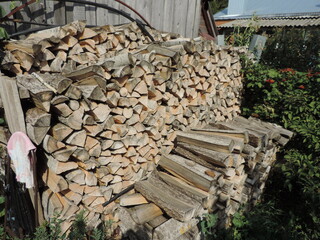 Stacked in a woodpile, chopped firewood for heating a private house.