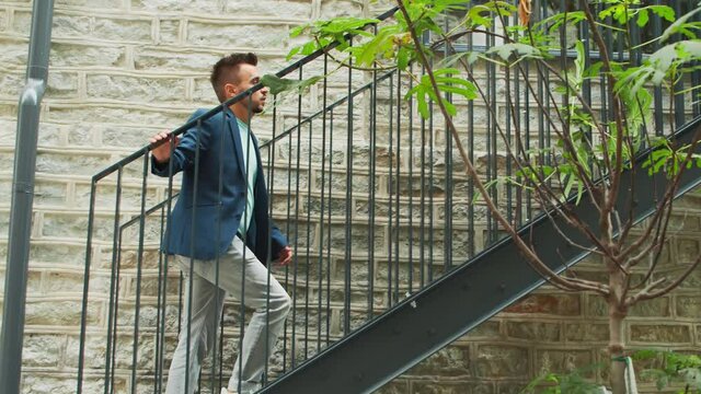 A young successful businessman is walking up the stairs. Man in a casual wear. Business, freelance and remote work.