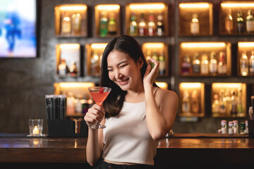 Beautiful woman is drinking orange cocktail and having enjoy to relaxing while smiling and sitting alone