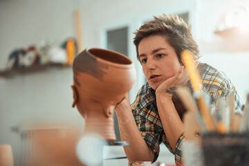 Nice female ceramist painting pottery in workshop