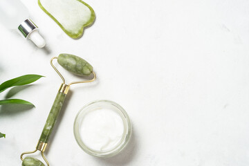 Scincare product. Jade roller and gua sha stone massager with face cream and serum bottle. Anti aging therapy. Top view. © nadianb