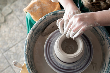 creating a clay pot on a potter's wheel, the potter's hand is viewed from above