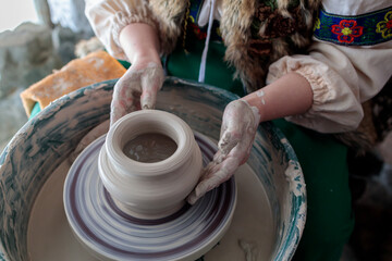in the national Slavic clothes the potter creates a product of clay