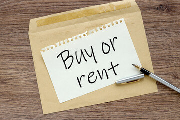 Buy or Rent? craft notebook on wood table with text on paper and pen