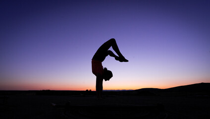 Silhouette of a teenage girl exercising, jumping, and gymnastics at sunset last night.
