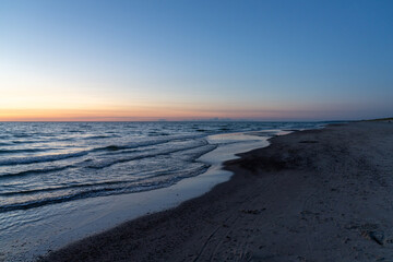 ocean sunset with sandy beach and wooden pylon storm groin in the foreground