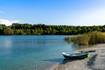 landscape of limestone  and calm blue groundwater lake in an old quarry with a small rowboat in the...