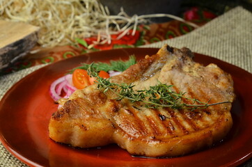 Dish for dinner with grilled meat and vegetables on red plate, close up view rustic background