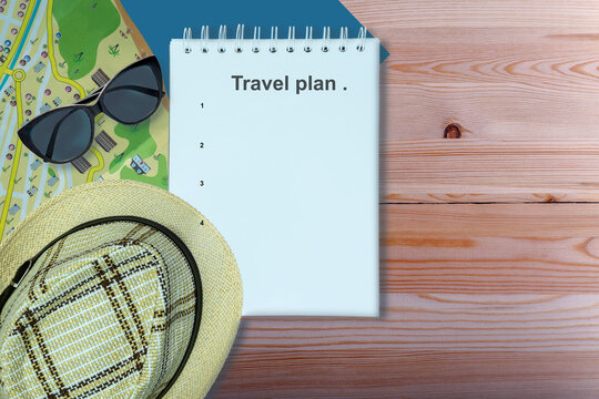 Travel planning. Hat, sunglasses and notebook on wooden table