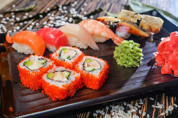 Various kinds of sushi and rolls served on black plate