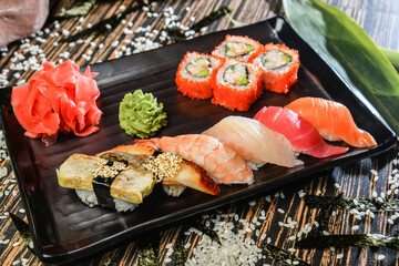 Various kinds of sushi and rolls served on black plate