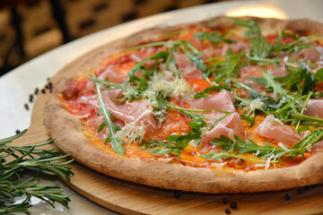 Delicious hot pizza with sliced meat and mushrooms served on wooden table with ingredients, close up view. Menu photo.
