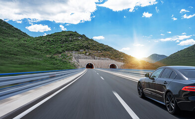 Black car on a scenic road. Car on the road surrounded by a magnificent natural landscape.