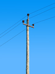 Old wooden power transmission pole with wires on a sky background