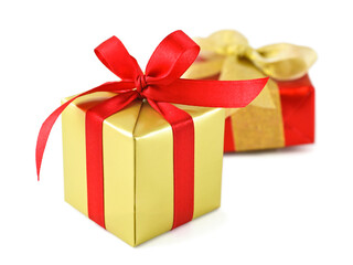 Golden gift wrapped presents with red satin ribbon bow on white