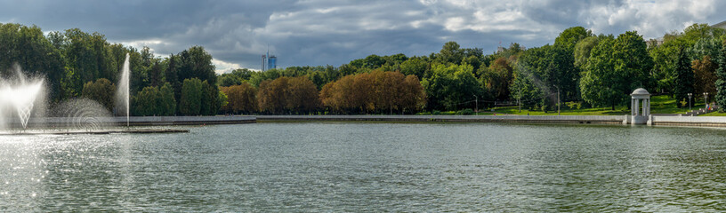 Water from the fountain. Top of high water stream of fountain behind cloudy sky. Fountain in river against dramatic sky. Cityscape view.
