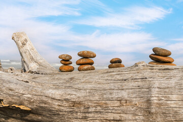 Carin of rocks stacked upon each other on a driftwood tree log at an ocean beach. 
