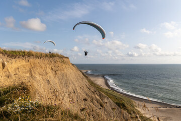 Two Paragliders soaring along the cliffs of Bovbjerg, Denmark during sunset.  Scenic view from top...