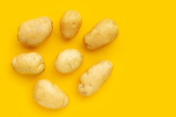Fresh potatoes on yellow background.