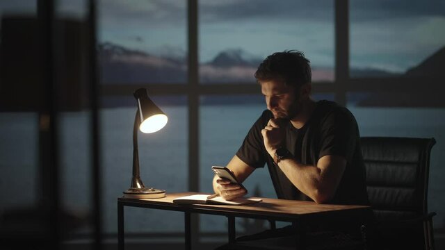 Silhouette of a man sitting at a table looking at a mobile phone thinking and analyzing the stock market, solving personal problems, repayment of loans, Internet banking