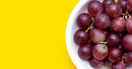 Fresh grape in white bowl on yellow background.