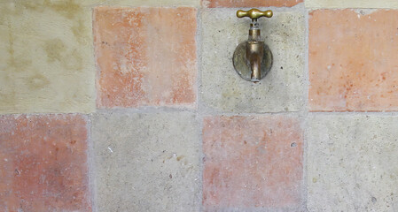 Vintage tiled wall in neutral colours with small old copper tap......