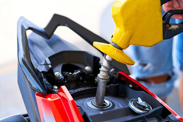 Refueling a motorbike. Close-up of a fuel nozzle inserted into a gas tank