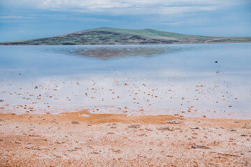 A lake with protrusions of pink-orange salt above the water. Koyashskoye Lake
