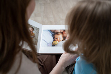 mother and daughter looking a book with photos from a family photo shoot