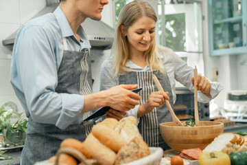 A woman and a man who are lovers are happy to help each other bake.