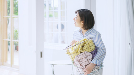 洗濯物を持った若い女性 © polkadot