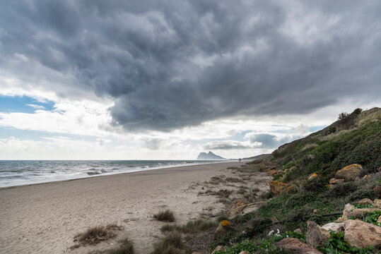 Paisaje de playa en La Linea de la Concepcion con nubes de tormenta y Peñon de Gibraltar al fondo, Cadiz, España