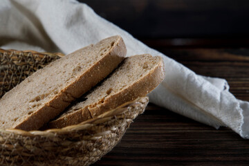 Slices of rustic bread in wicker bowl on a wood table