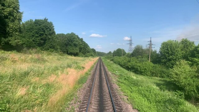 blured side view of high-speed turning end back of train on landscape of beautiful nature wild field and mountains forest on clean sunny day in summer. Transport, travel, railway, communication