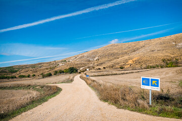 View of the Hill outside Castrojeriz with Way Marker Scallop Shell and Yellow Arrow Signs along the Pilgrim Way of St James Pilgrimage Trail Camino de Santiago