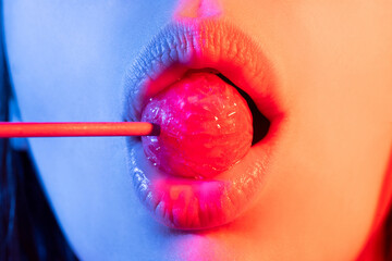Close up of model with lollipop in mouth, dramatic lighting - obrazy, fototapety, plakaty