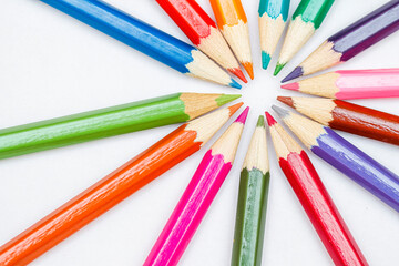 Fototapeta premium coloured pencils arranged in a radial shape with the tips pointing towards the centre, back to school concept