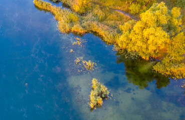 Fototapeta na wymiar A small island on the lake with yellow autumn trees.